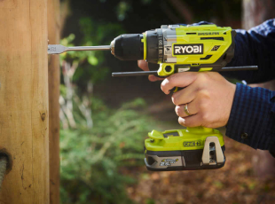 Eine Person bohrt mit einem Ryobi-Akkubohrer in ein Holzbrett