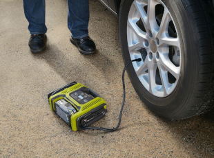 Ein tragbarer Kompressor pumpt einen Autoreifen auf