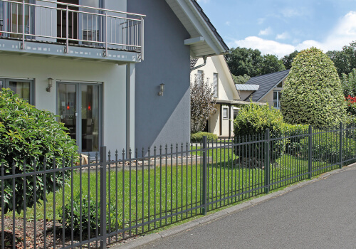 Ein modernes Haus mit Garten und Metallzaun im Vordergrund