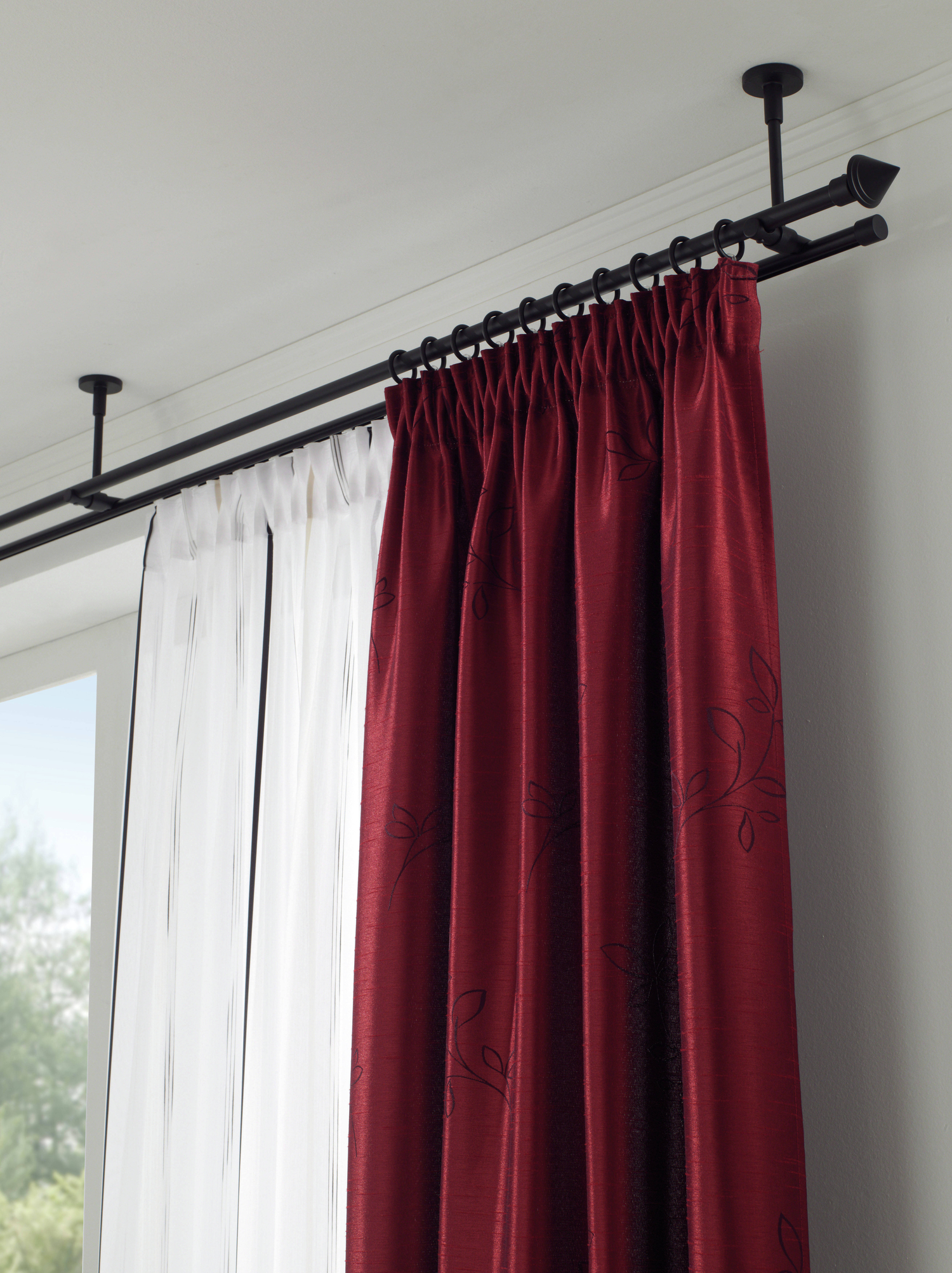 Rote Vorhänge neben weißen Gardinen an einer schwarzen Gardinenstange
