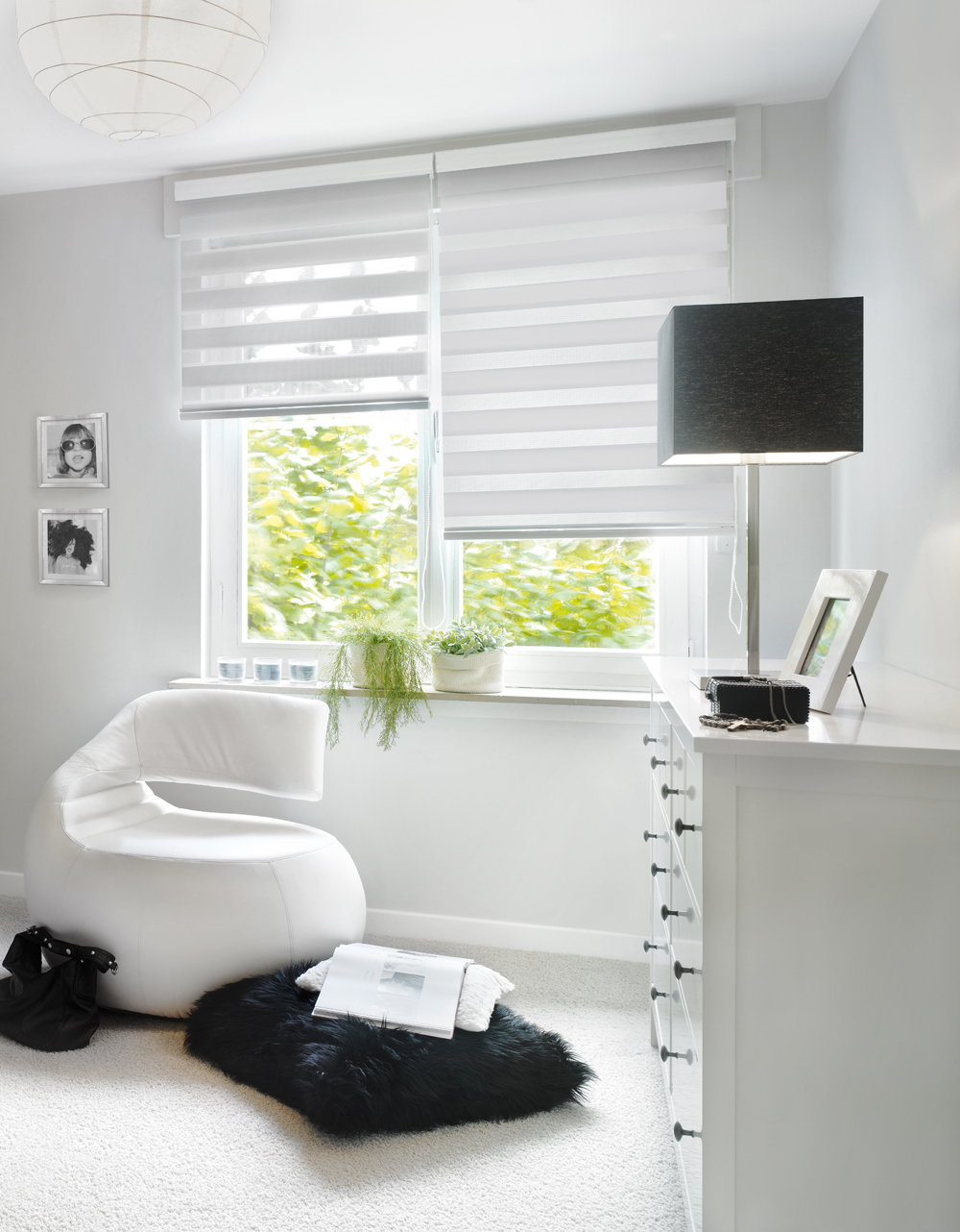 Helles Zimmer mit modernem Sessel, Kommode und großem Fenster mit Blick ins Grüne