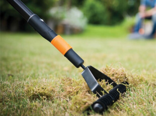 Ein Rasenlüfter entfernt Moos von einer Rasenfläche