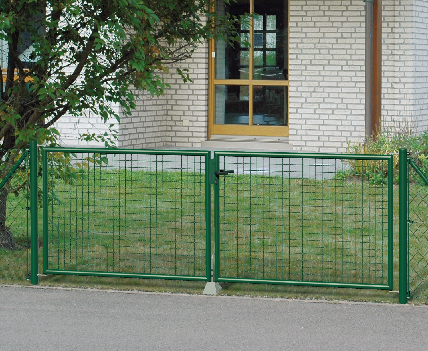Ein grünes Maschendraht Gartentor vor einem Haus mit Grünstreifen