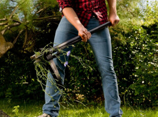 Person entfernt Unkraut mit einem Gartenwerkzeug im Freien