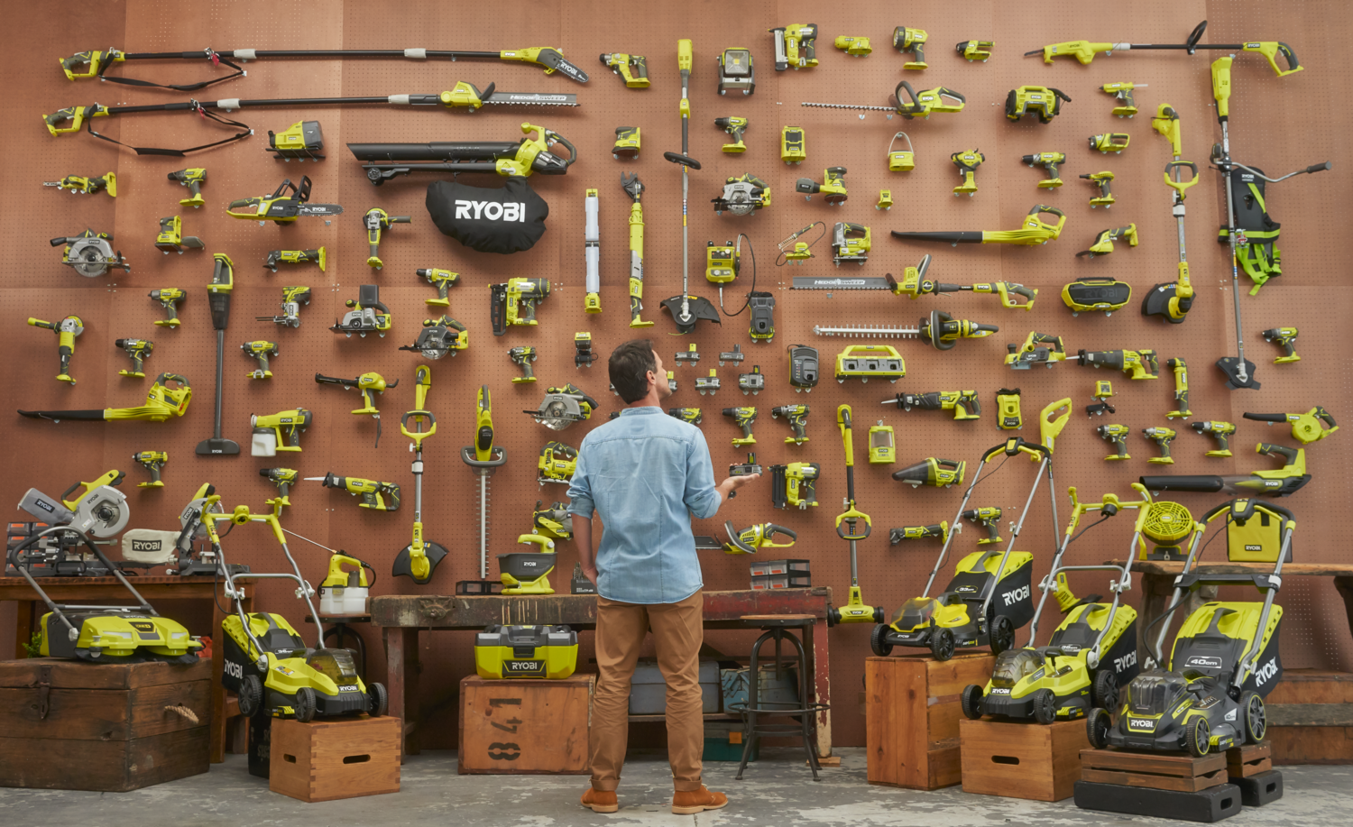Ein Mann steht vor einer Wand voller Ryobi-Werkzeuge