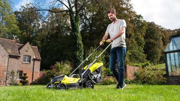 Mann mäht Rasen mit einem Rasenmäher im Garten