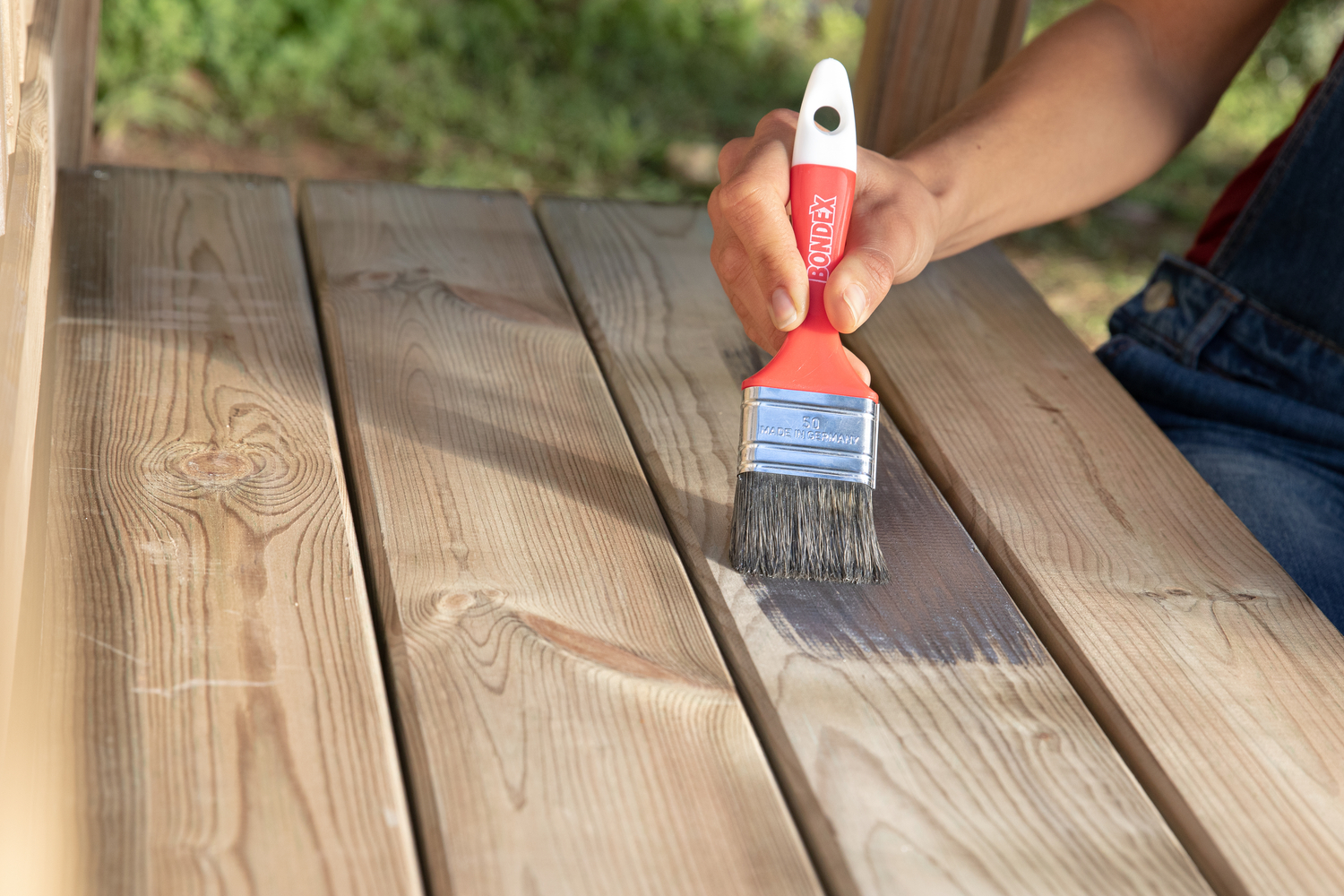 Eine Person streicht eine Holzoberfläche mit einem Pinsel an