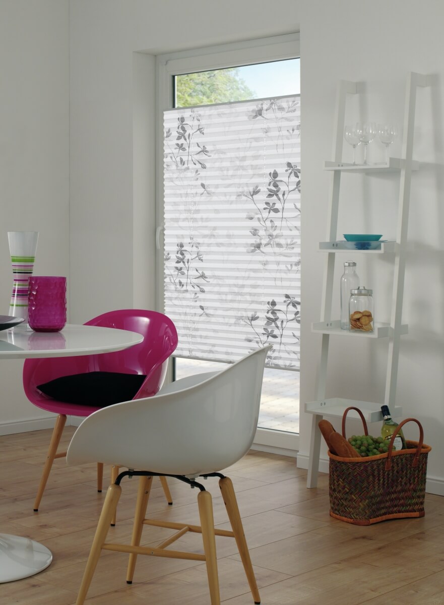 Moderner Essbereich mit bunten Stühlen und einem Fenster mit floralem Plissee-Rollo