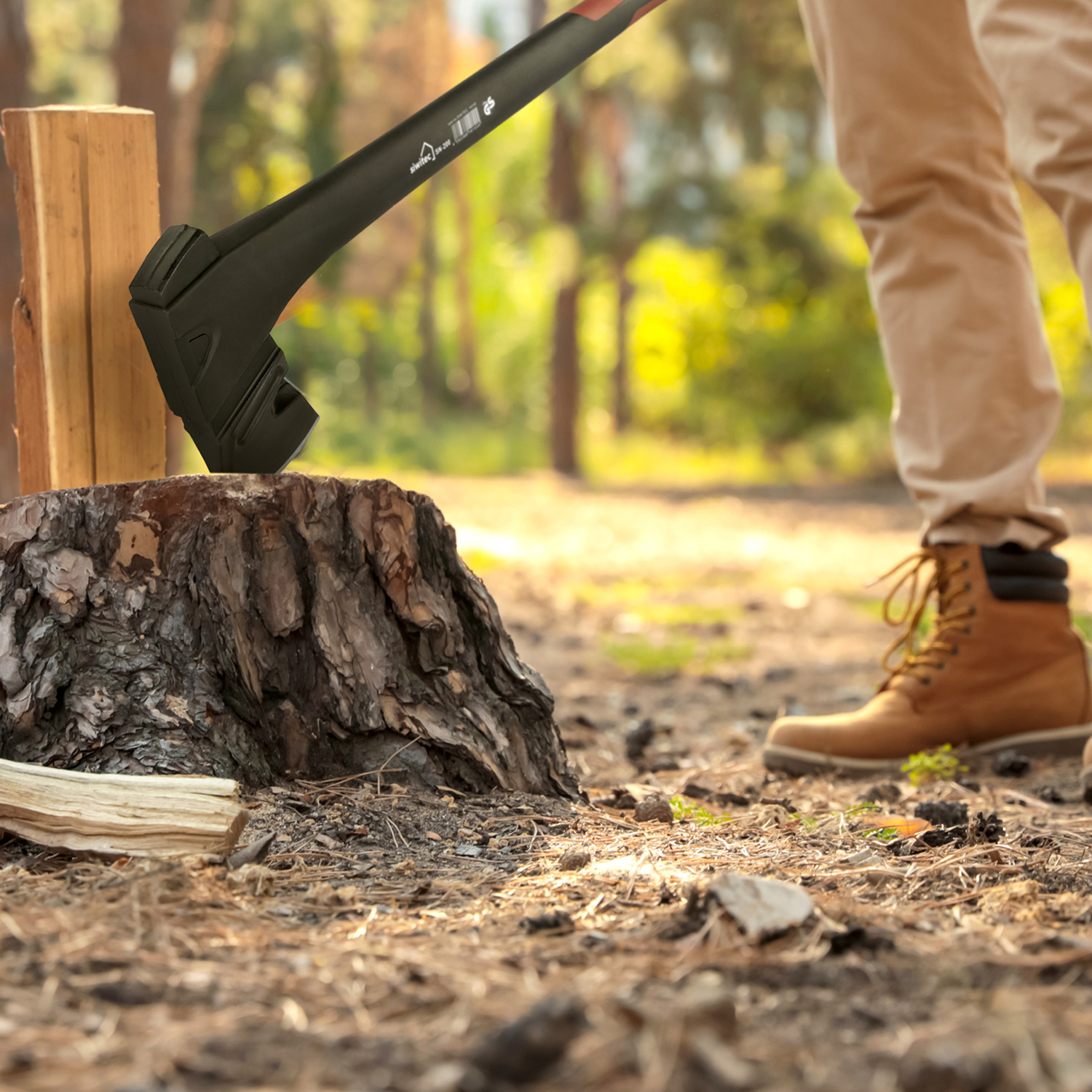 Person spaltet Holz mit einer Axt im Wald